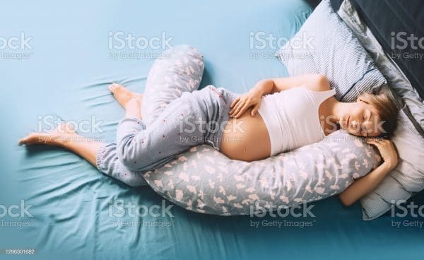 Beautiful Pregnant Woman Relaxing Or Sleeping With Belly Support Pillow In Bed. Young Mother Waiting Of A Baby. Concept Of Pregnancy, Maternity, Healthcare, Gynecology, Medicine.