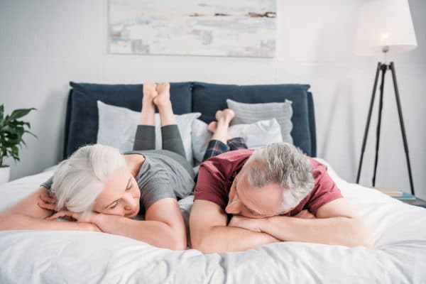 Senior Wife And Husband Sleeping In Bed Together At Home