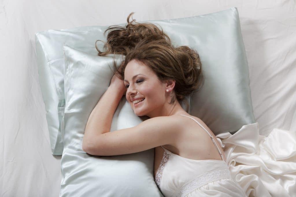 Portrait from high angle view of a cheerful young woman relaxing in her bed.