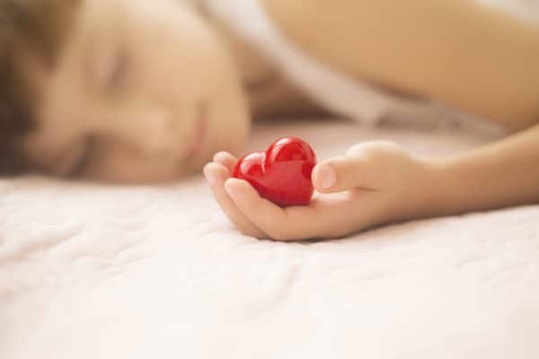Child Sleeping Holding Plastic Heart